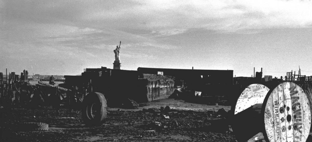 Statue of Liberty seen from abandoned piers and industrial waste at Liberty State Park, 1977
