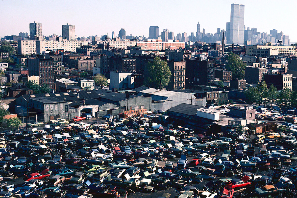 Junked cars in the Hoboken Auto Body lot with the World Trade Center in the background, 1978