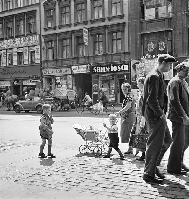 Street scene with a swastika flag in the background, Berlin, 1930s.