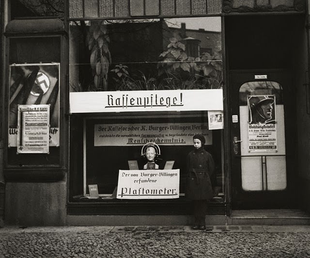 Mara Vishniac posing in front of a shop specializing in instruments that measure skulls, Berlin, 1933