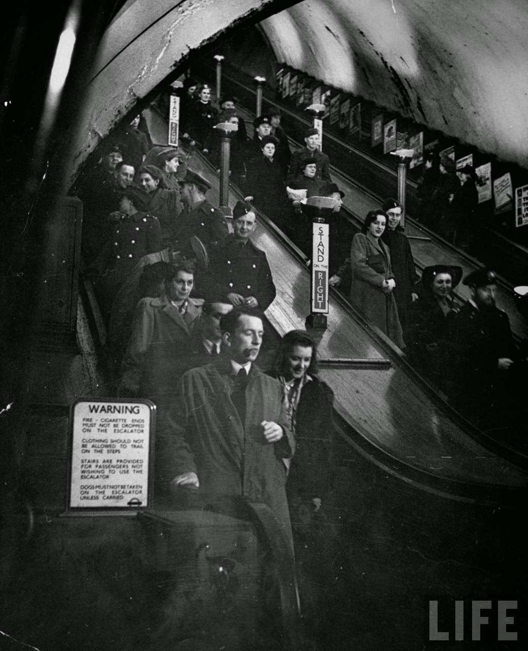 Night-lifers, servicemen, and war workers on escalators at Piccadilly Circus underground station during World War II, 1940s