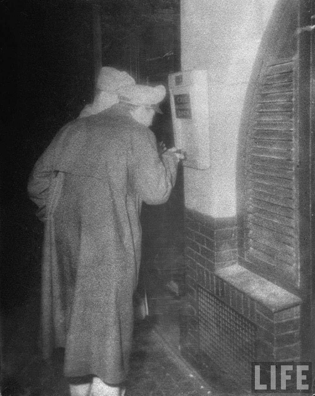 Soldiers using a torch to examine a restaurant menu on lower Wardour Street, 1940s