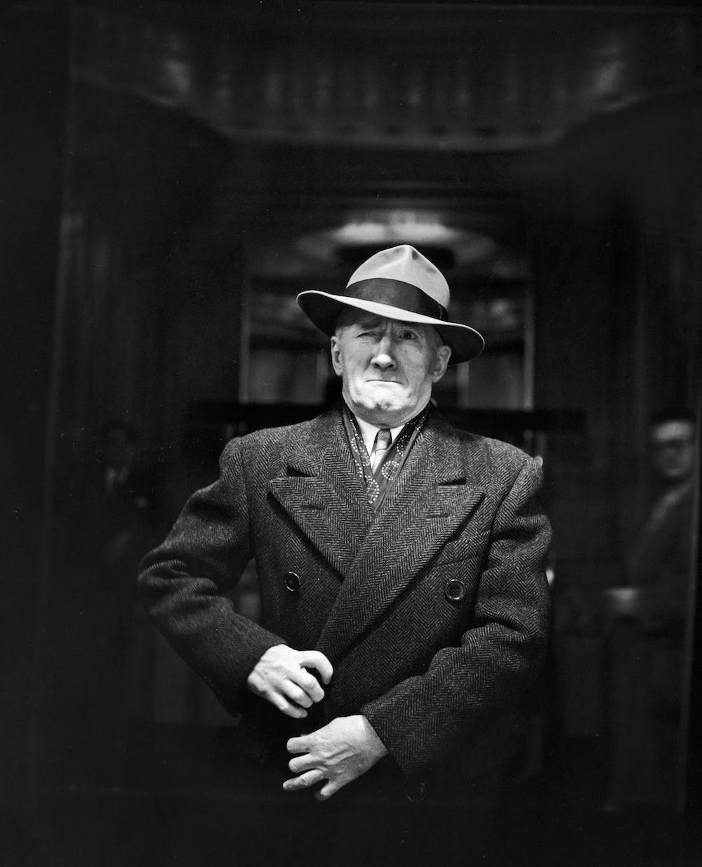 Man adjusting his overcoat and grimacing