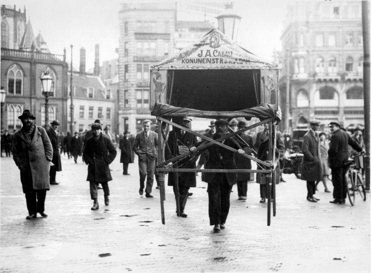 Puppet player carrying his Punch-and-Judy show / puppet show theatre across the Dam square in Amsterdam, the Netherlands. 1935.