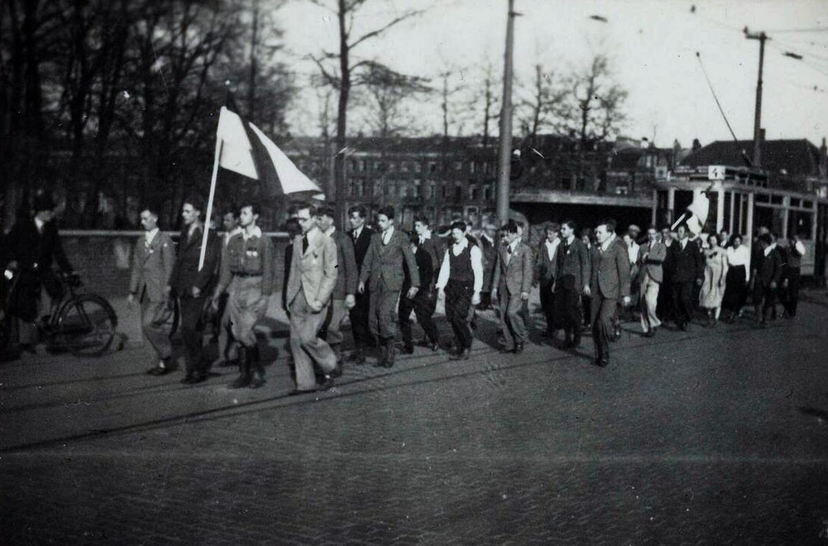 NSB procession with a man carrying the Dutch flag in front of a tram, 1930s