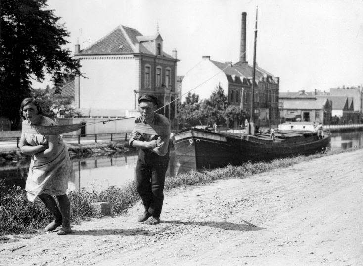 Man and woman towing a cargo-boat through a ship-canal. The Netherlands, 1931.