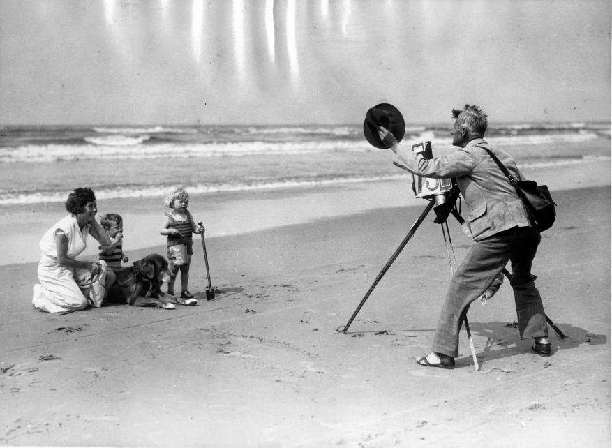 Beach photographer taking pictures of mother, children and a dog. The Netherlands, about 1930.