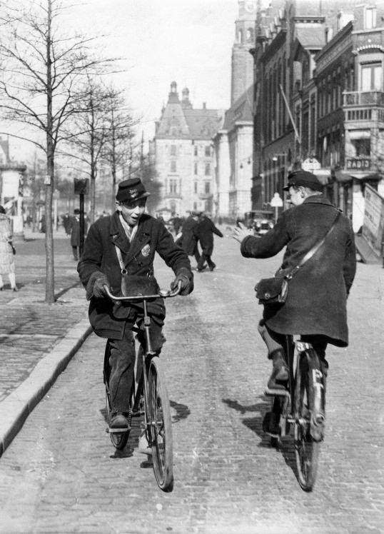 Telegram deliverers on bicycle greeting each other in the street. The Netherlands, Place unknown, early 1930's.