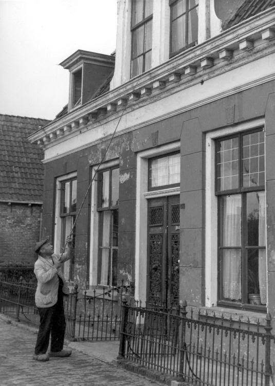 Caller-up waking up inhabitants by tapping a stick at the bedroom window. Leeuwarden, the Netherlands, 1947.
