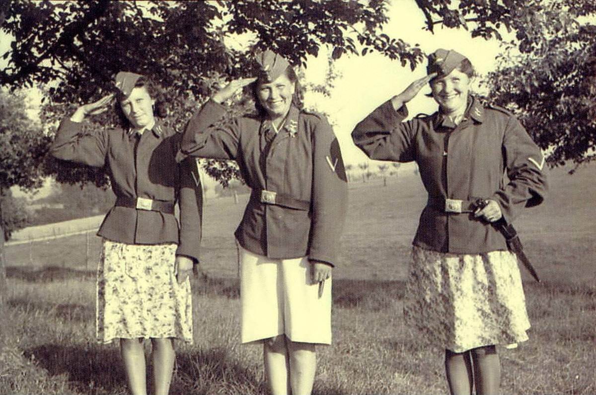 Three Dutch women in German uniform jackets in a meadow, 1942