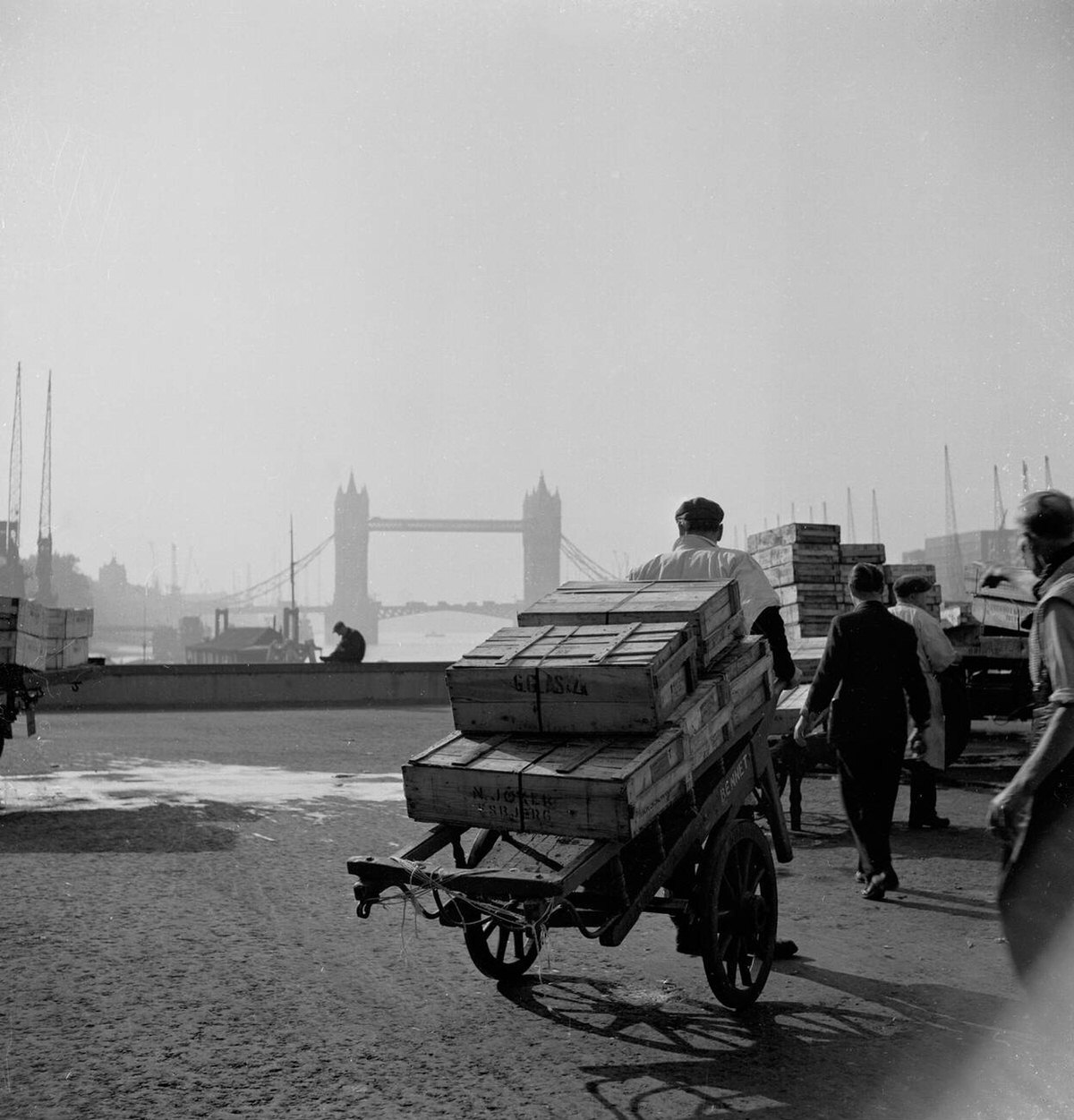 Market porters pulling carts across London Bridge with Tower Bridge in the distance, 1950s