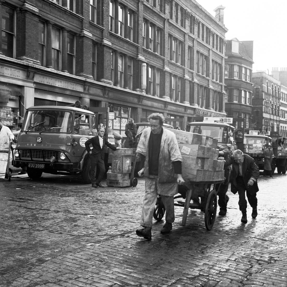 Porter pulling a heavily loaded trolley up a cobbled street at Billingsgate Fish Market, 1950s