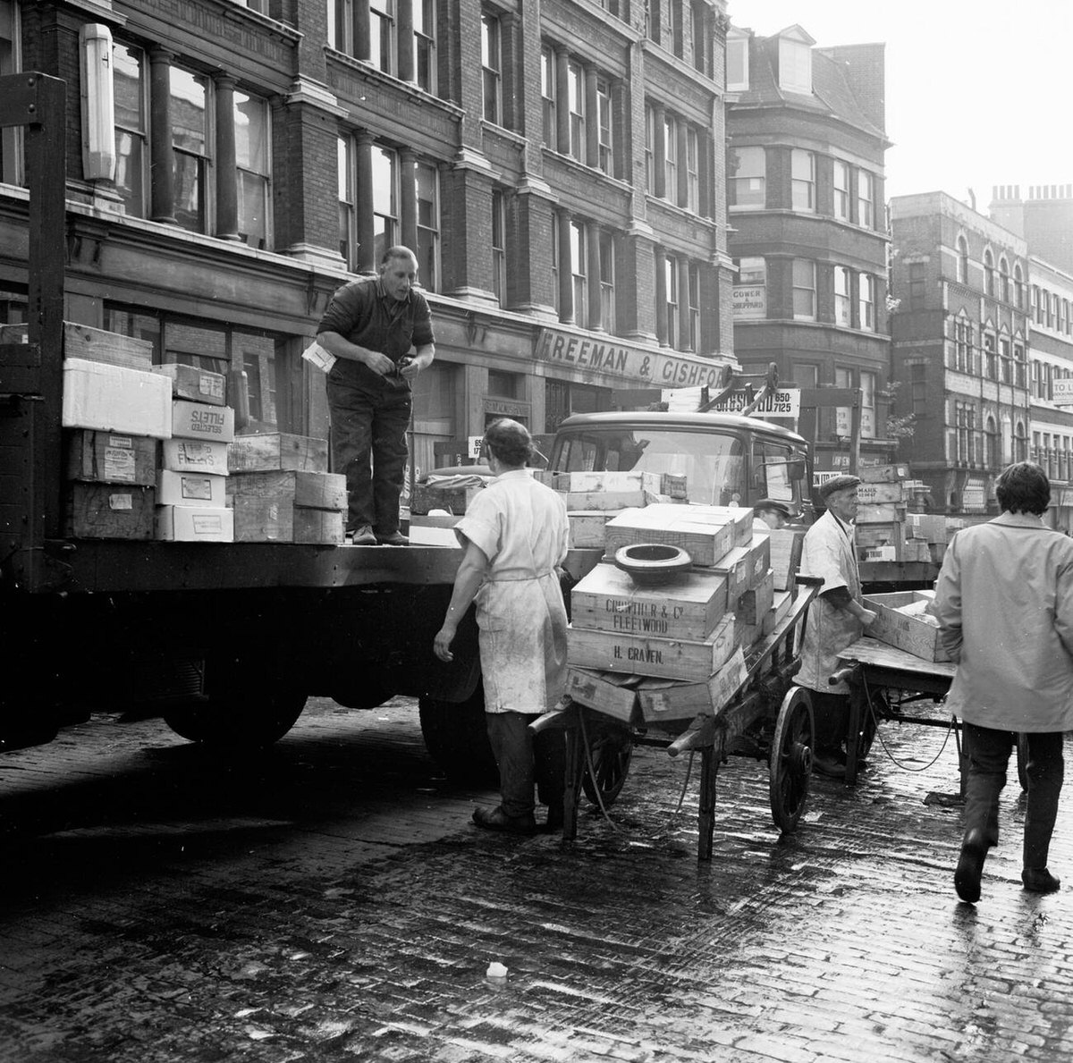 Porters unloading fish from a lorry onto carts on Lower Thames Street, 1950s