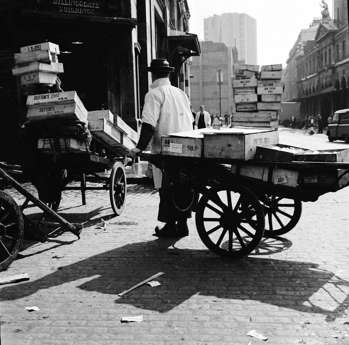 Porter pulling a wooden cart loaded with crates of frozen fish on Lower Thames Street, 1950s