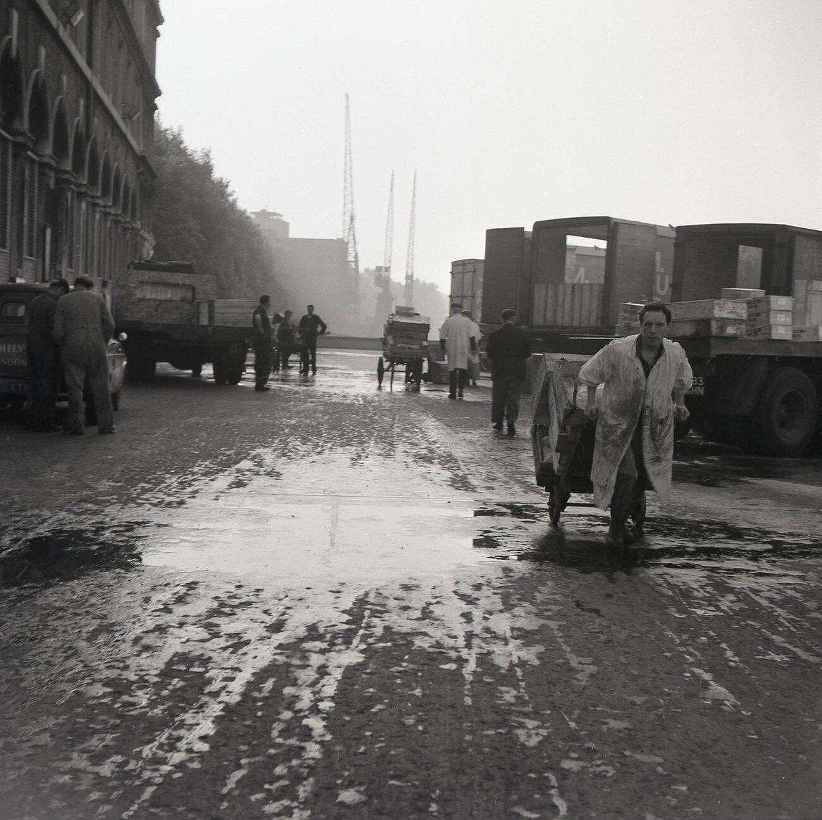 Market porter pulling a cart loaded with trays of fresh fish outside Billingsgate Fish Market, 1950s