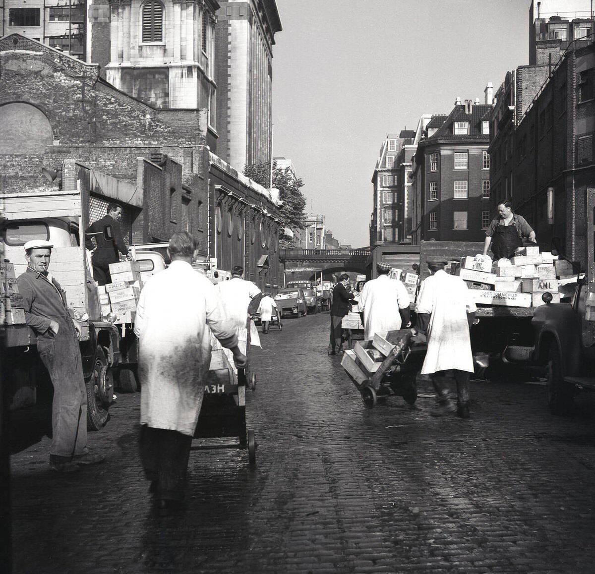 Market porters moving crates on a cobbled street outside Billingsgate Fish Market, 1950s