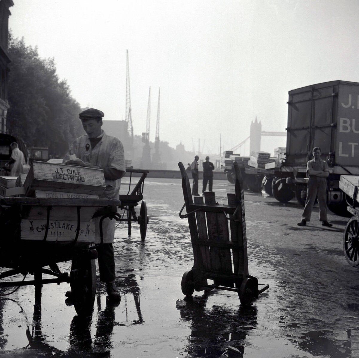 Workers loading crates of fish for Billingsgate Fish Market on a wet London Bridge, 1950s