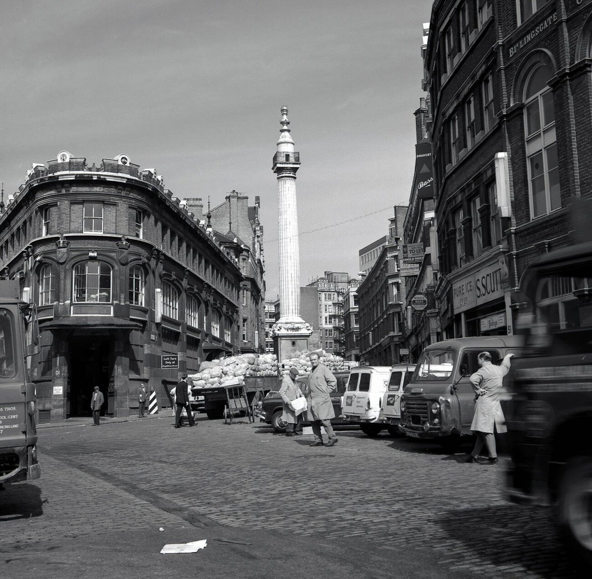 Cobbled street with trolleys and vans outside Billingsgate Fish Market on Thames Street, 1950s