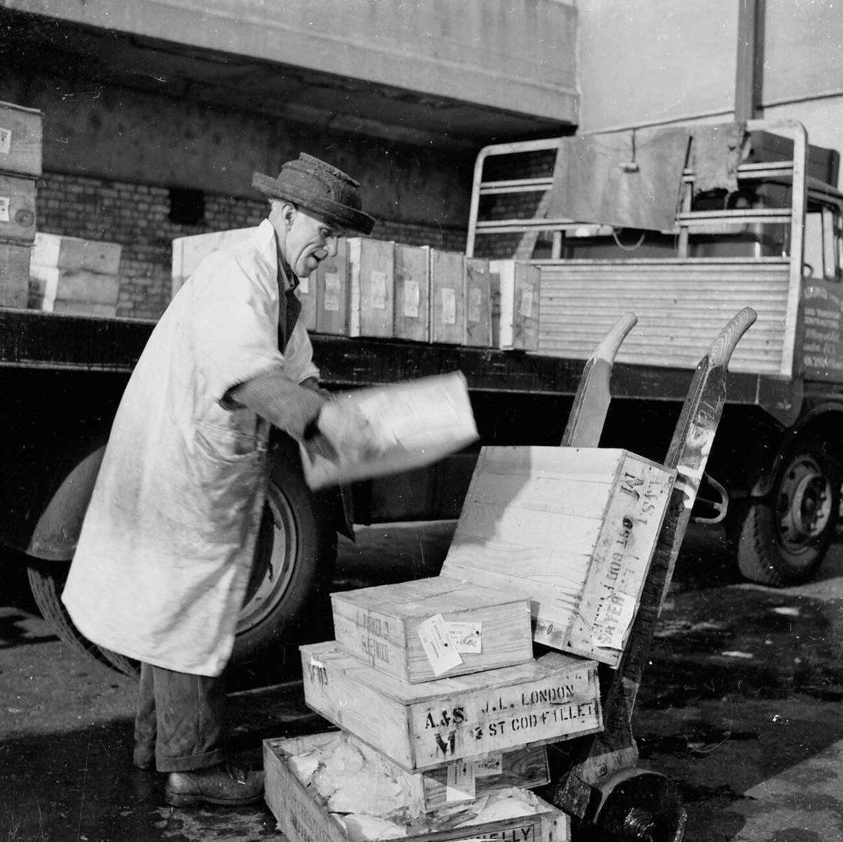 Porter loading crates of fish onto a trolley at Billingsgate Fish Market, 1950s