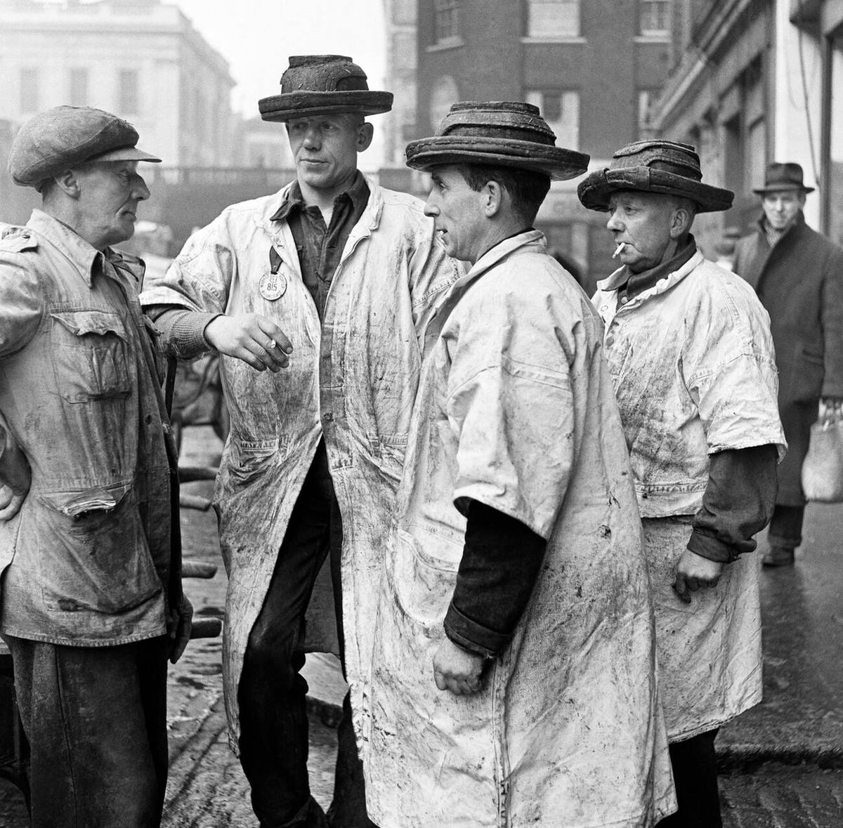 Three fish porters in distinctive hats discussing trade at Billingsgate Fish Market, 1954