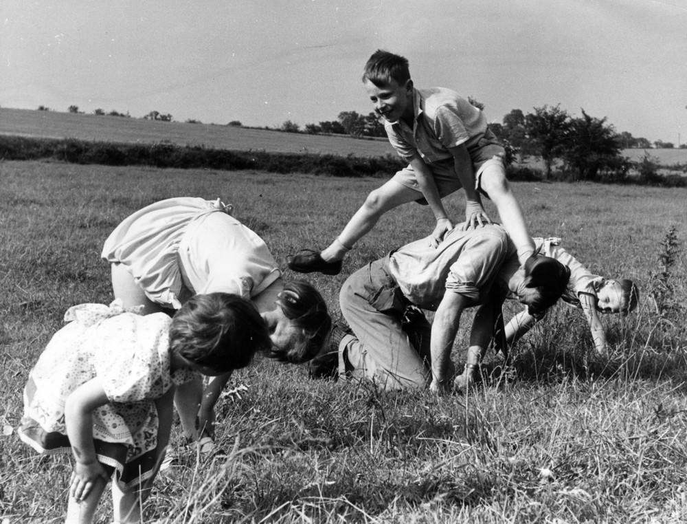 People playing leapfrog in a field, 1955