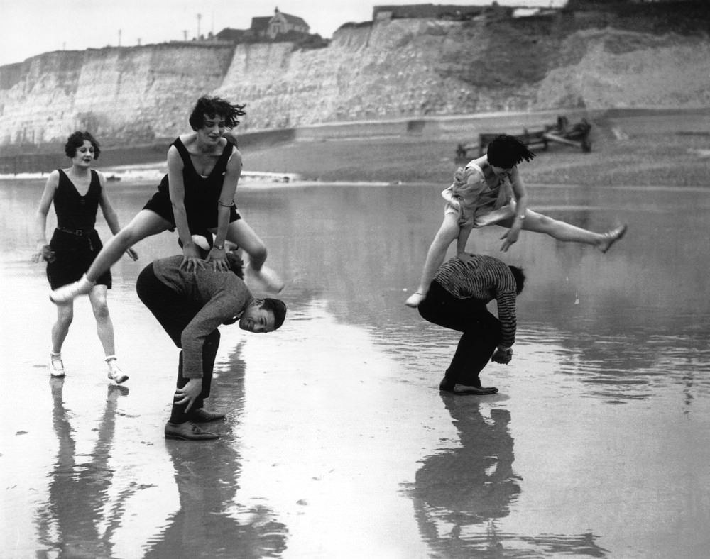 Members of the Brighton Swimming Club playing leapfrog on the beach, 1925