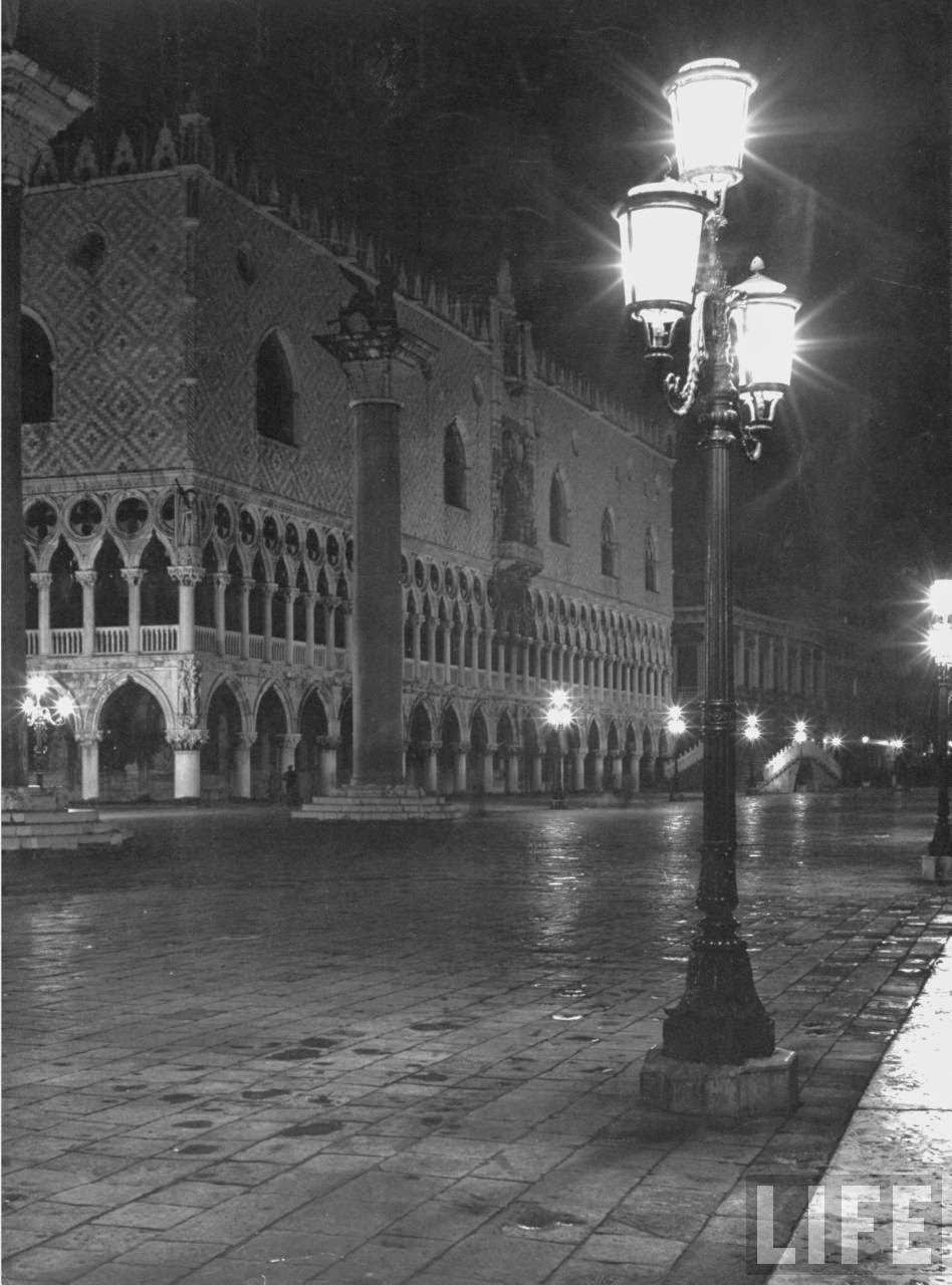 Night lit by elegant street lights in a flooded Piazza San Marco next to the Doge's Palace after a heavy rain.