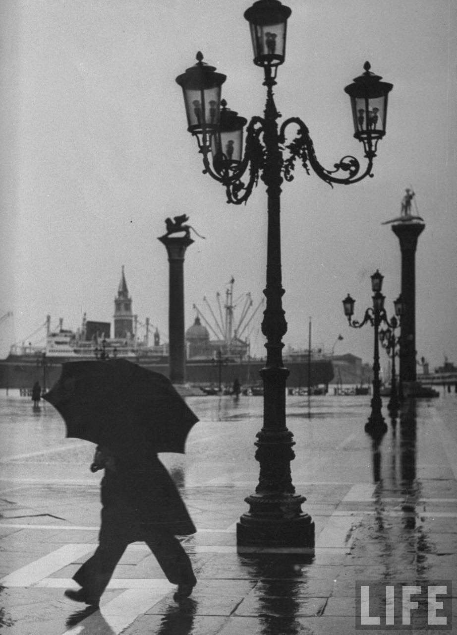 Pedestrian on a rainy day in Piazza San Marco w. Grand Canal in background.
