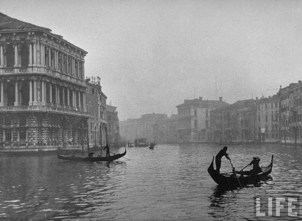 Winter fog hanging over travelers by gondola on Grand Canal amidst the venerable bldgs. of this ancient city.