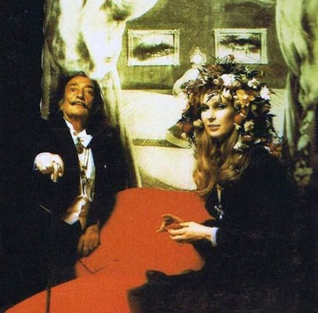 Salvador Dali doing his Dali face in front of his famous depiction of Mae West.