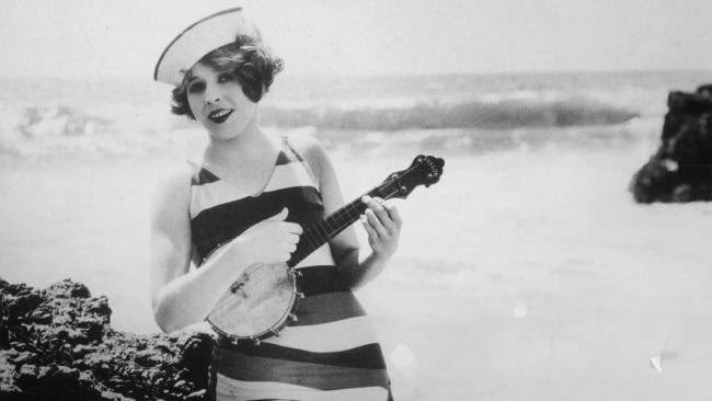 Girl in a striped swimsuit and sailor's hat playing the banjo, 1923