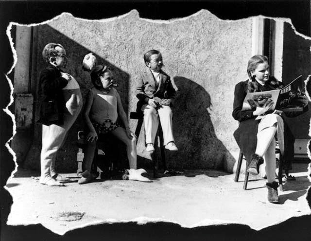 Judy Garland reading Life magazine on set with Munchkin actors, The Wizard of Oz, 1939