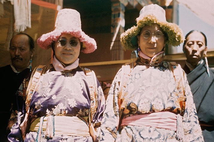 The Dalai Lama's mother and sister defy convention with Western glasses. Dekyi Tshering (right), once a humble farm wife, rose to an awesome position as Tibet's "Great Mother" when her son became Dalai Lama in 1940. She and her daughter wear brocade hats fringed with silk. Eyeglasses were taboo in the god-king's presence.