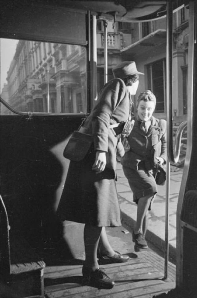 Mrs Day is helped by a female conductor onto the bus that will take her to work. This photograph was probably taken on Fulham Road.