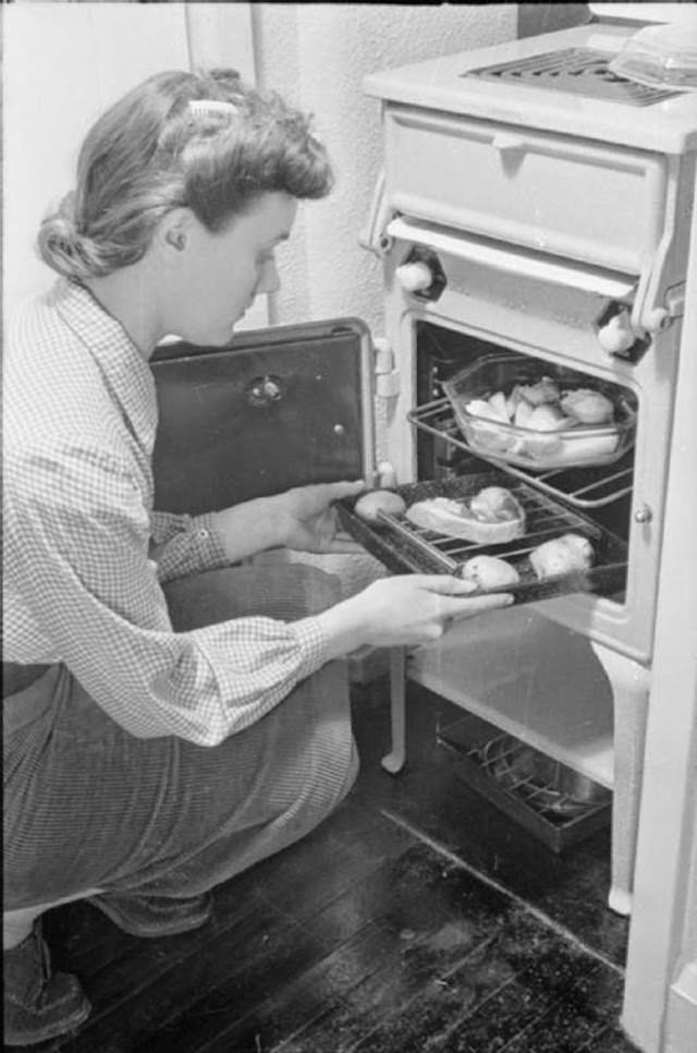 Mrs Day puts her dinner into the oven after a busy day. The Ministry of Food encouraged people to cook their entire meal in the oven as a way to save fuel.