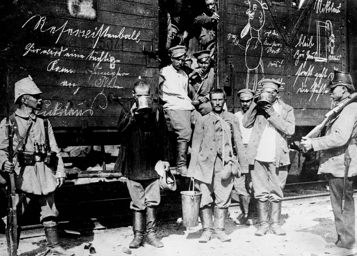 Russian prisoners drinking from large cups by a railroad car in East Prussia, 1914