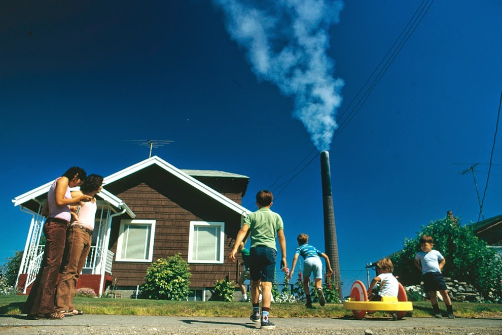 Children play in the yard of Ruston home, while a Tacoma smelter stack showers the area with arsenic and lead residue, Ruston, Washington, 1972