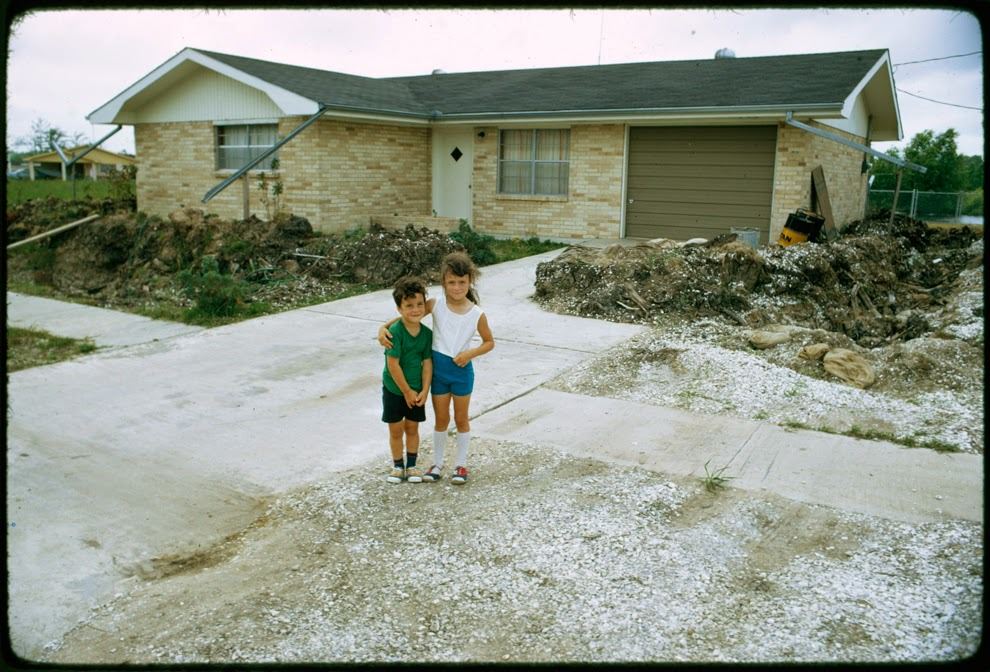 Stevensville children in front of a trenched house. Owner dug trench and formed levee to protect house from flood waters, Stevensville, Louisiana, 1973