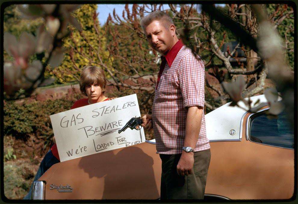 Country's fuel shortage led to problems for motorists in finding gas as well as paying much more for it, and resulted in theft from cars left unprotected. This father and son, made a sign warning thieves of the possible consequences, Portland, Oregon, 1974