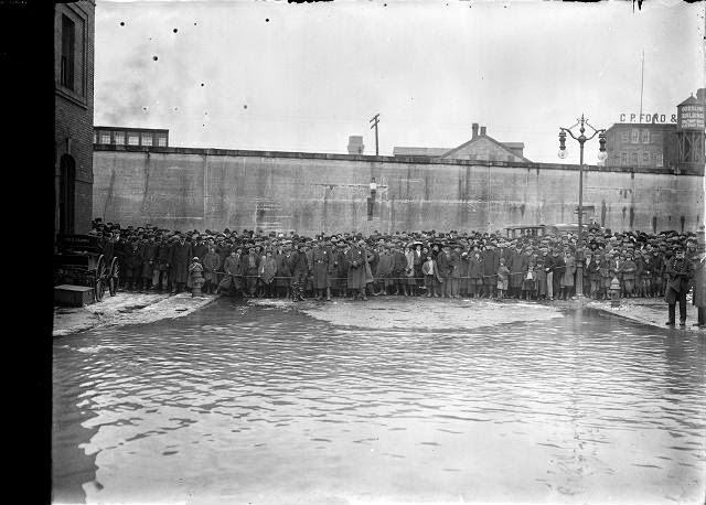 Police hold back a large crowd at the water's edge on flooded Front Street, 1913