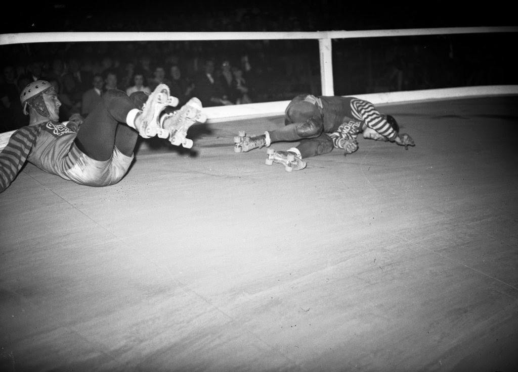 Louis Stasiuk of the New York roller derby team and Paul Gorski of the Chicago roller derby team tangle and spill during the sixth annual roller derby that opened at the Coliseum, 1940s