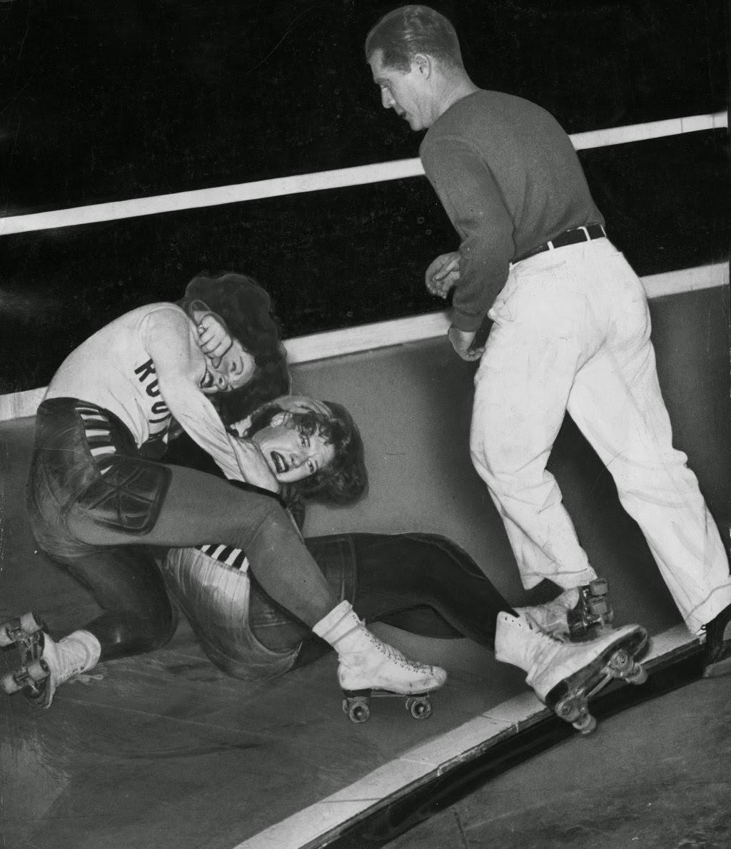A referee goes in to break up a skirmish during a Coliseum match between Virginia Balzer of the Chicago team and Virginia Ogden of the California team, where the referee revealed the loss of some hair and a few loose teeth, 1940s