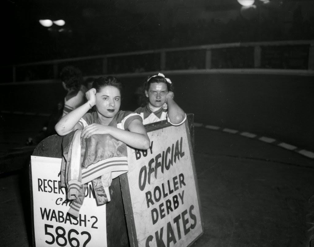 Chicago Westerners Roller Derby skaters Ann Pernice and Eleanor Weber watch from the penalty box at the Coliseum at a Roller Derby, 1950s