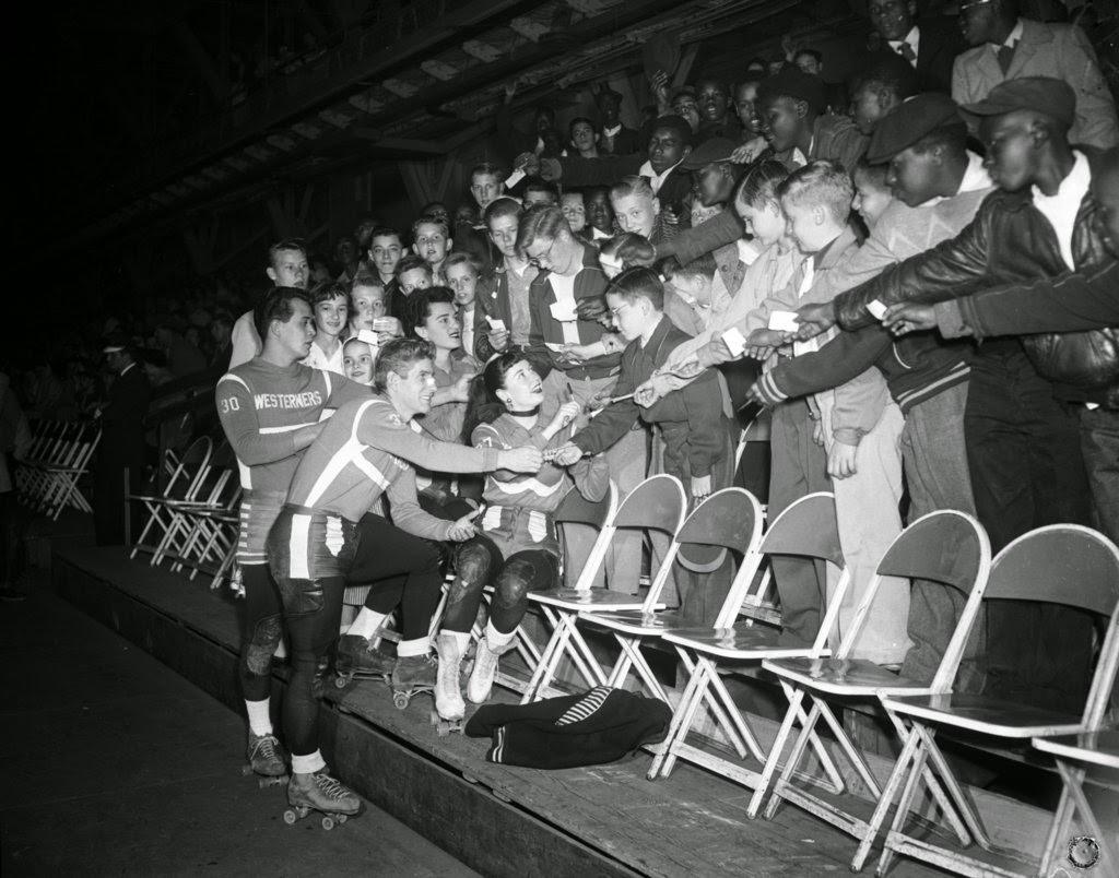 News carriers wave their tickets to get autographed from Fred Noa, Bert Wall, Dolores Doss and Bobbie Mateer of the Chicago Westerners roller derby team at the Coliseum, 1950s