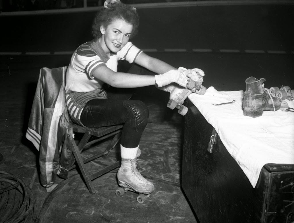 Mary Gray, a member of the Chicago Westerners roller derby team, repairs her skates between periods at a roller derby at the Coliseum, 1950s