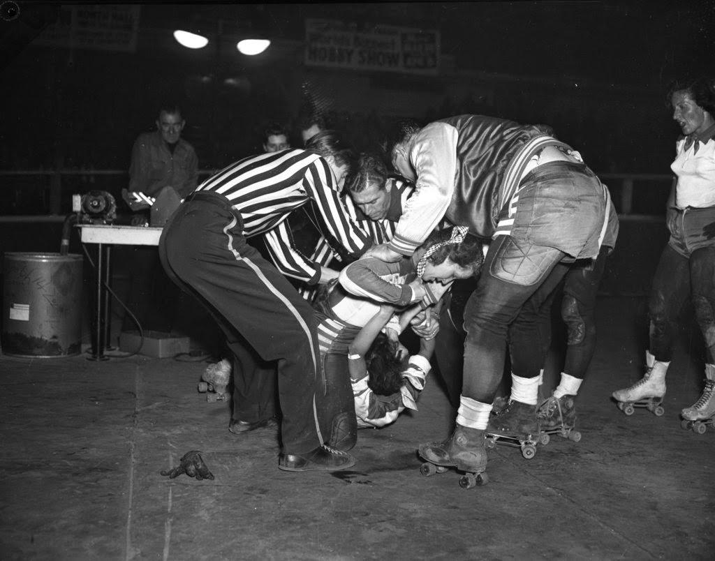 Referees and skaters try to pry loose Mary Lou Palermo of the Jersey team from the grip she has on the hair of Betty Boyd of the Chicago Westerners in a roller derby at the Coliseum, 1950s