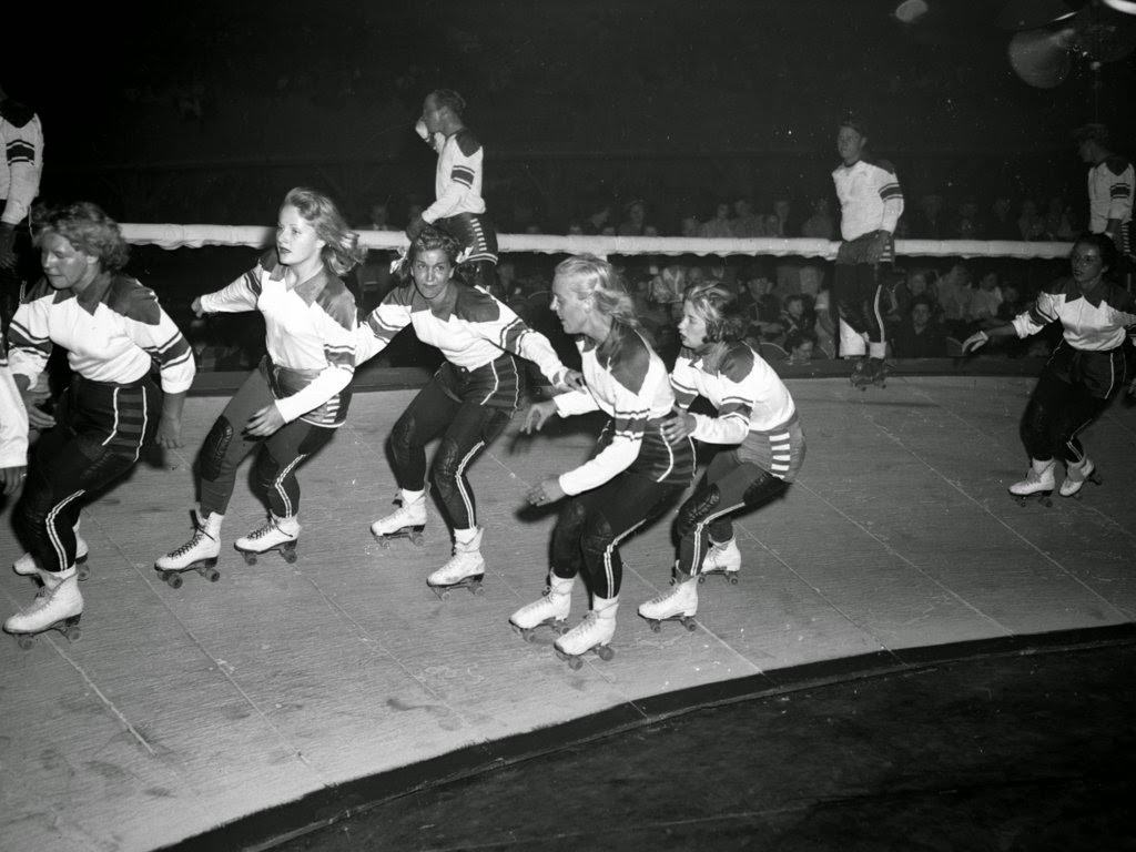 Women speed on a banked track during a roller derby in Chicago, 1900s