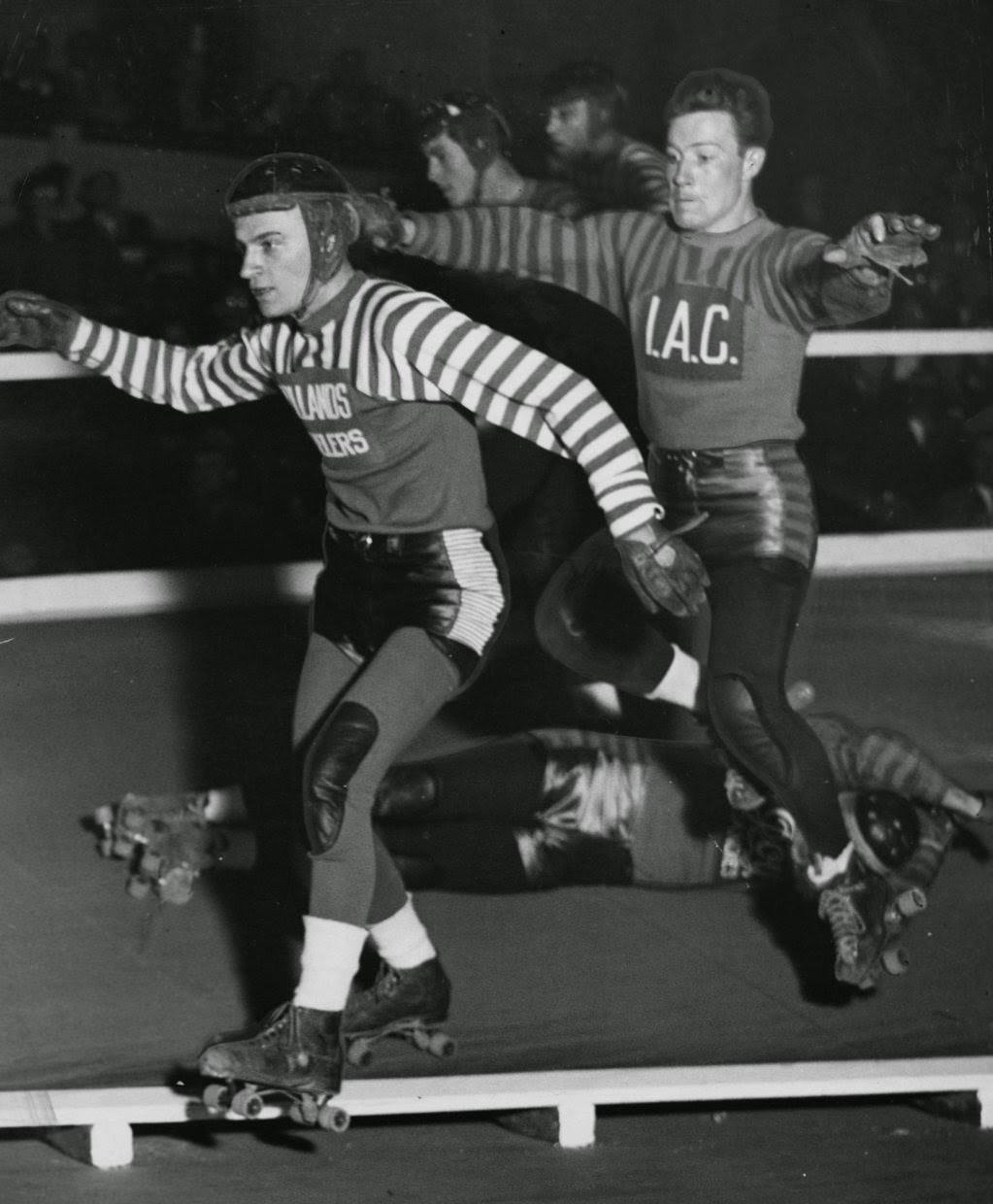 Bill Bogash and Bob Satterfield step over a fallen skater during a Coliseum match, 1940s