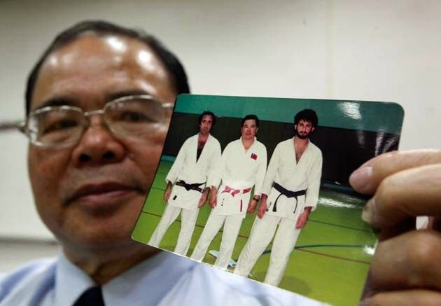 Taiwanese coach Jimmy Wu poses with what Wu says is a photo of himself (C, in picture) with Osama Bin Laden (R, in picture) dressed in their judo gi, during an interview with Reuters in Taichung, 2011